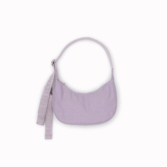 It is made of durable nylon and features a zippered main compartment, an interior slip pocket with integrated keyleash, and an adjustable shoulder strap. The bag has a curved shape that hugs your body and a sleek design that adds a touch of elegance