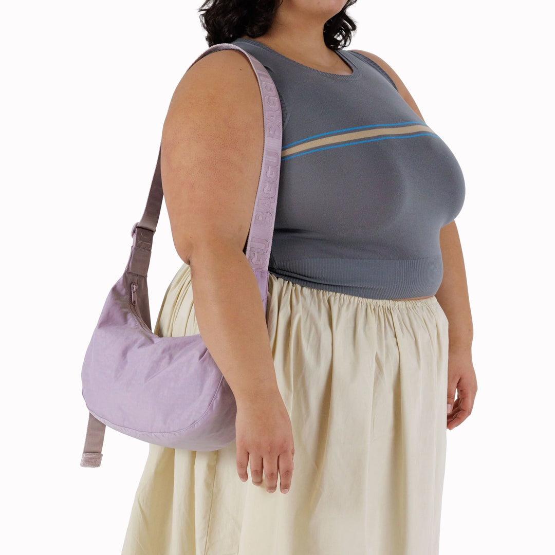 The Medium Crescent Bag in Dusty Pink from Baggu is a stylish and versatile accessory that can complement any outfit. It is made of durable nylon and features a zippered main compartment, an interior slip pocket, and an adjustable shoulder strap.
