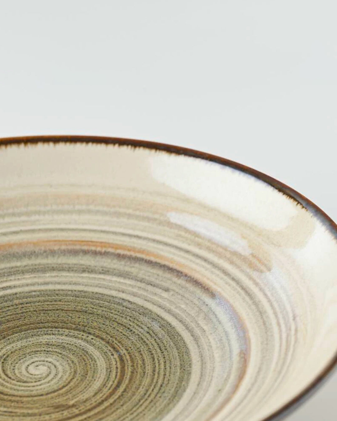 Shallow noodle bowl with irregular earthy toned swirl pattern on a cream glazed base. Diameter 23cm and height approx 5cm.