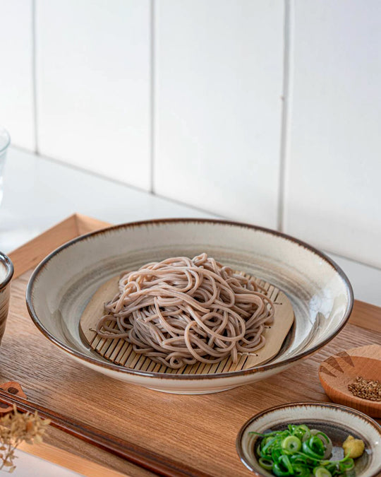 Shallow noodle bowl with irregular earthy toned swirl pattern on a cream glazed base. Diameter 23cm and height approx 5cm.