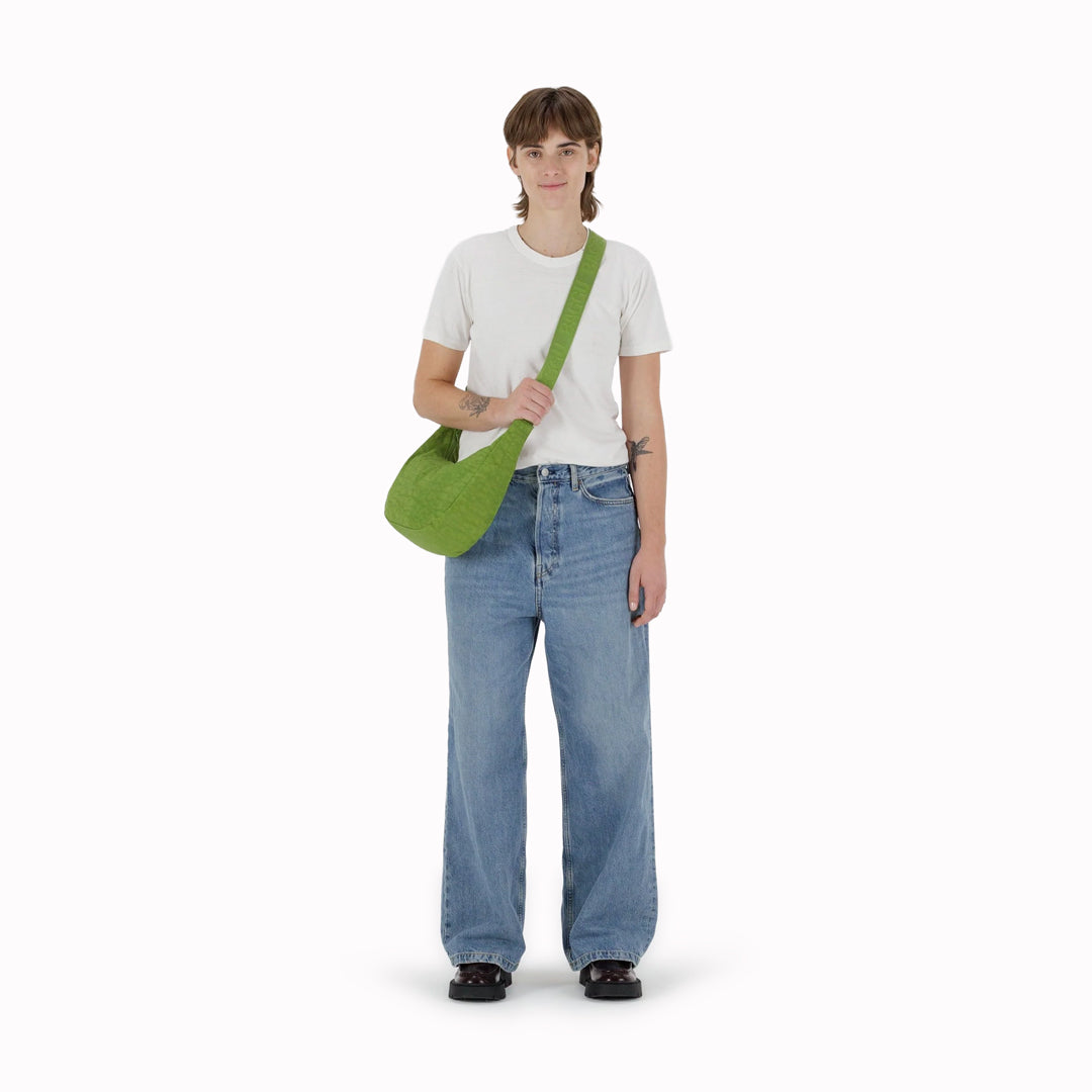 The Medium Crescent Bag in Green Juice from Baggu is a stylish and versatile accessory that can complement any outfit. It is made of durable nylon and features a zippered main compartment, an interior slip pocket, and an adjustable shoulder strap.