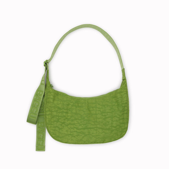 The Medium Crescent Bag in Green Juice from Baggu is a stylish and versatile accessory that can complement any outfit. It is made of durable nylon and features a zippered main compartment, an interior slip pocket, and an adjustable shoulder strap.