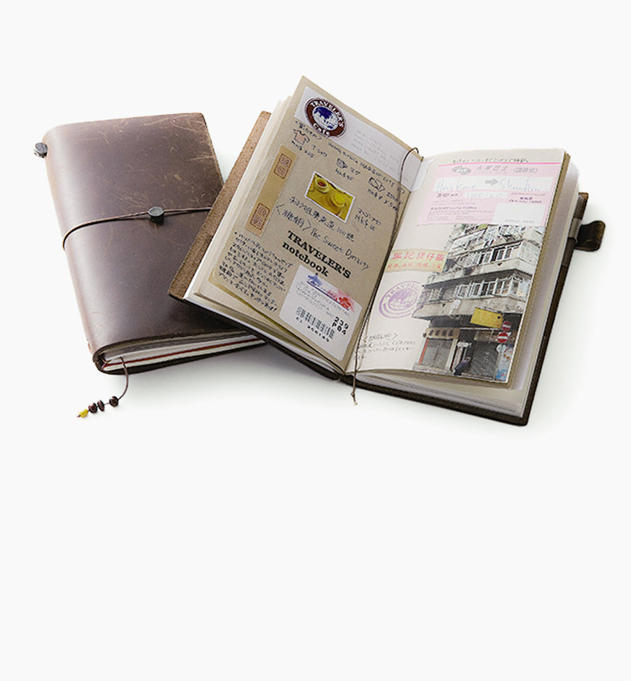 Aged and worn brown leather Travelers Co notebook from Japanese stationery brand Midori with notebook open showing details of a travel journal