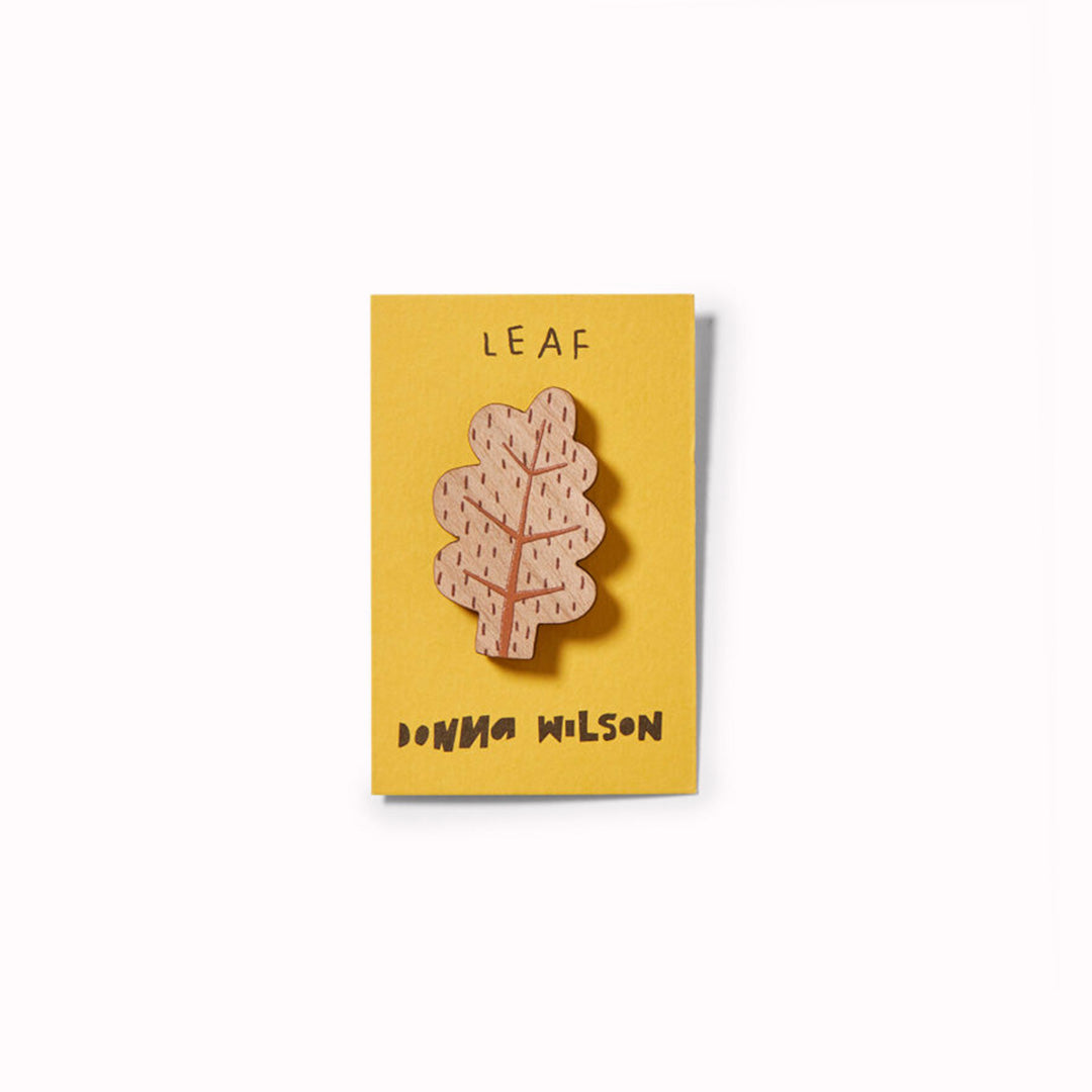 Leaf shaped wooden pin badge by Donna Wilson, printed with her Autumn Oak Leaf illustration. A tactile alternative to enamel pin badges