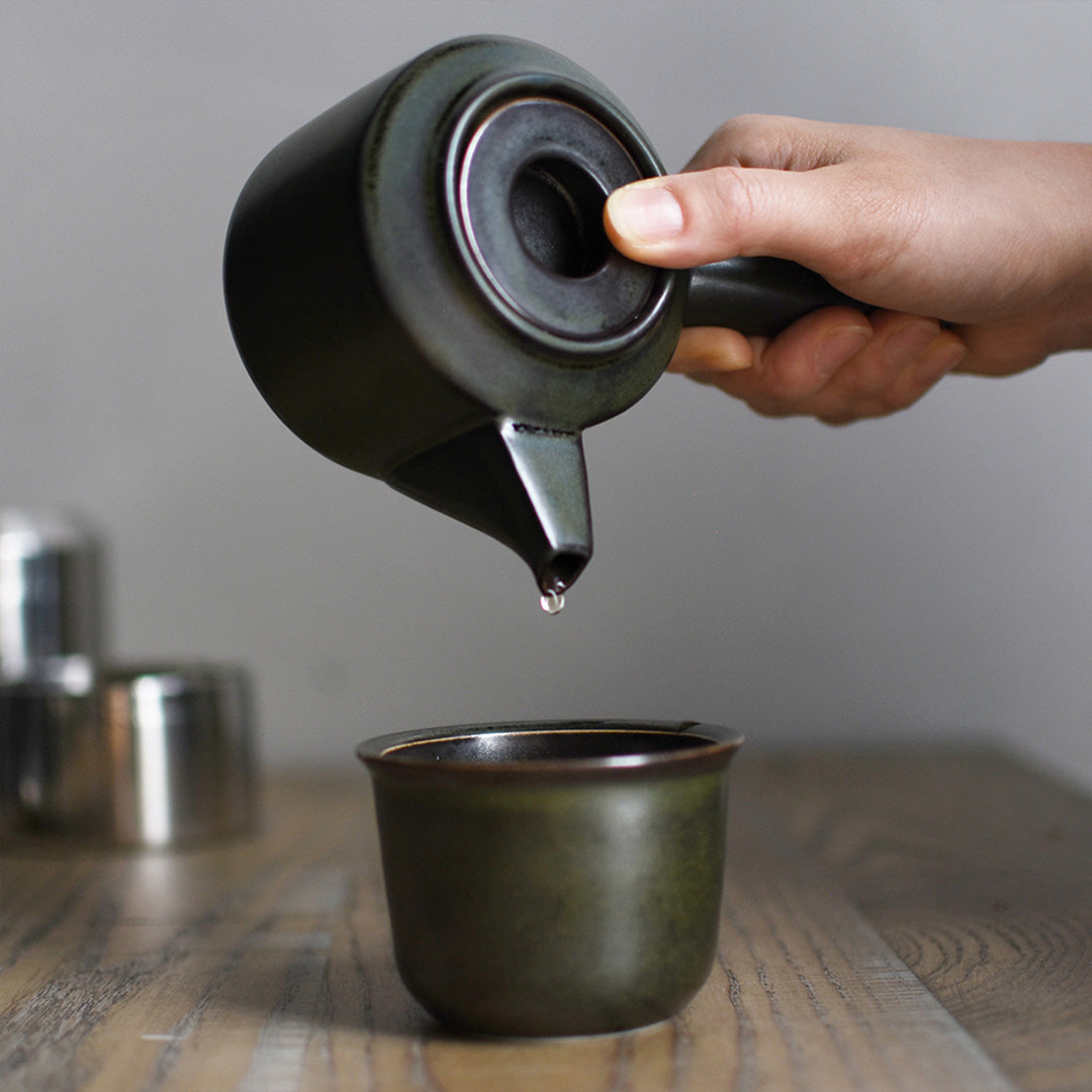 The Leaves to Tea teapot from Kinto is made of black porcelain, and features a sleek design that blends well with any tableware. The teapot has a large side handle that is easy to grip and a spout that pours smoothly.  It holds 300ml and is perfect for making a single cup of tea. Detail of teapot being poured.