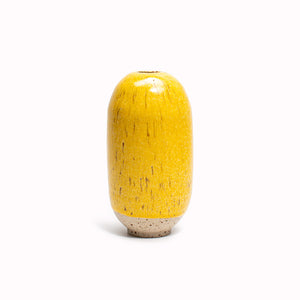 The bright yellow lemon zest design is hand-thrown in watertight stoneware. Due to the rounded taper at the top of the vase, the glaze melts down the sides of the cylindrical vase mimicking melting ice.
