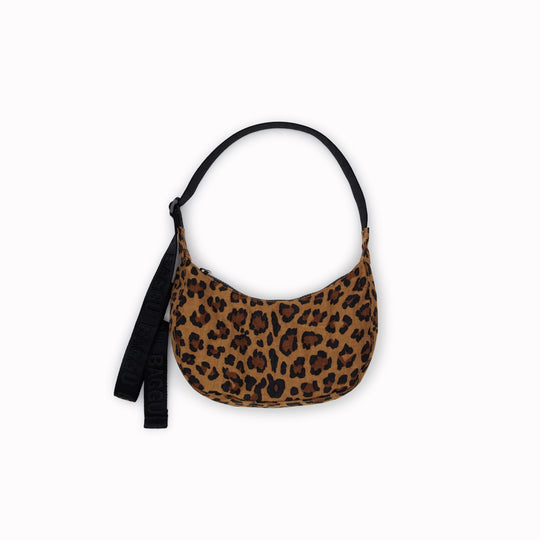 It is made of durable nylon and features a zippered main compartment, an interior slip pocket with integrated keyleash, and an adjustable shoulder strap. The bag has a curved shape that hugs your body and a sleek design that adds a touch of elegance