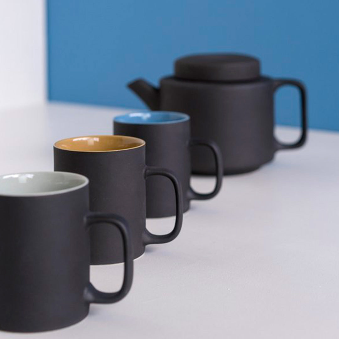 Collection of cups with extra large stoneware teapot from Dutch company Kinta who produce contemporary ceramics and homeware. The extra large teapot is black, with a soft matt exterior finish. Its design is influenced by ceramic trends of the 1960s, but with a pleasing modern and neutral colour palette.