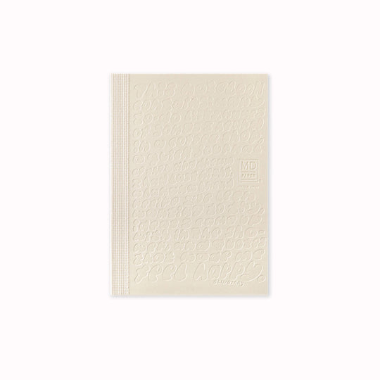 Cover of A6 plain paper notebook has an off white cover embossed with some ace artwork by Lindsay Arakawa featuring a hand type design, cutely filling the cover with things that could be written in the notebook. The MD paper logo is also embossed. 