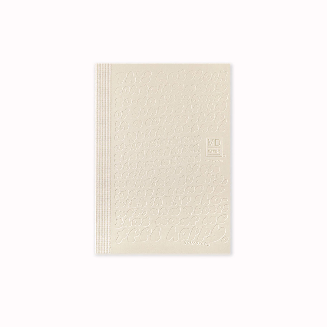 Cover of A6 plain paper notebook has an off white cover embossed with some ace artwork by Lindsay Arakawa featuring a hand type design, cutely filling the cover with things that could be written in the notebook. The MD paper logo is also embossed. 