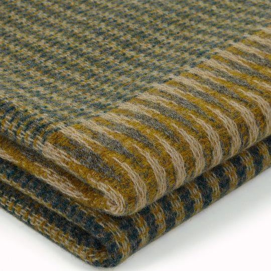 The Lismore Throw is a luxurious piece from Wallace &amp; Sewell, a British design studio known for its exquisite woven textiles. This particular tweed throw is made from 100% Shetland lambswool, creating a soft and cozy texture perfect for snuggling under on a chilly evening.