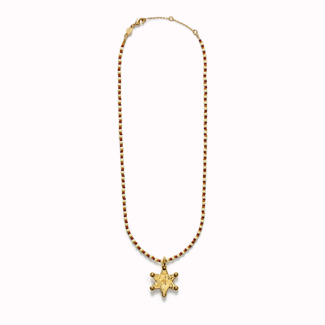 The Anni Lu Lucky Star necklace is a gold Western inspired star shaped gold pendant with glass beaded necklace chain in neutral hazel brown, rust and ecru colours.