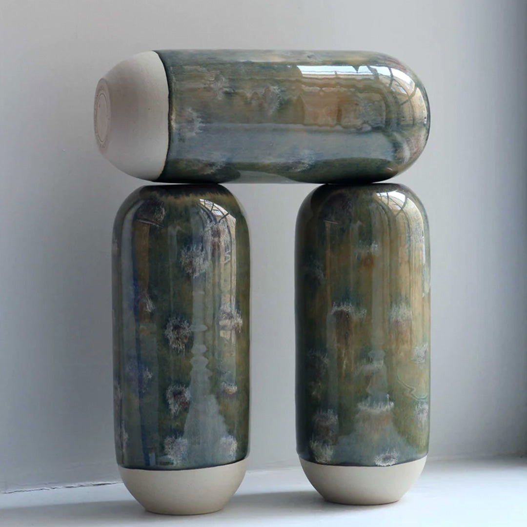 The deep green hued Marshland design is hand-thrown in watertight stoneware and due to the rounded taper at the top of the vase, the glaze melts down the sides of the cylindrical vase mimicking melting ice.