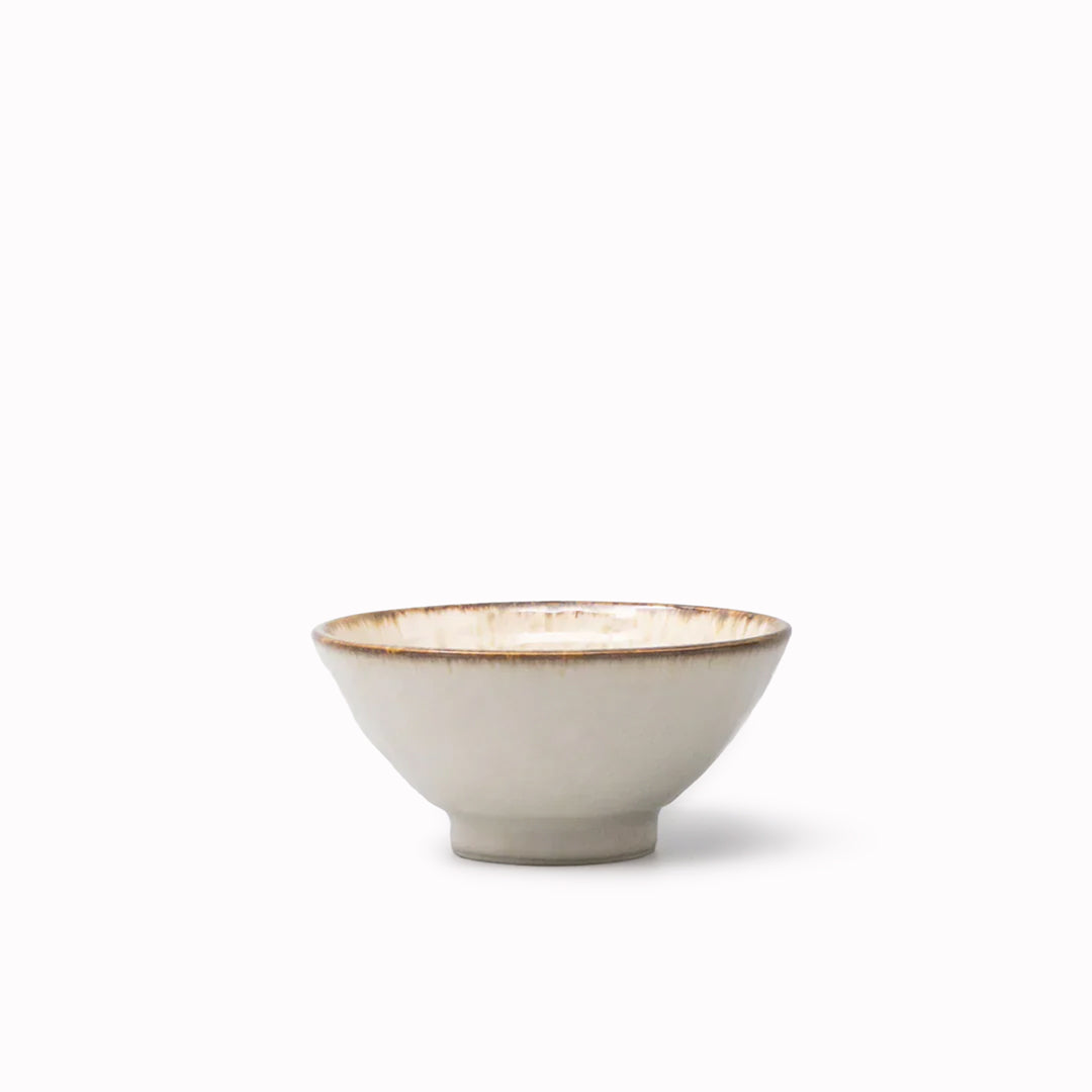 A handcrafted ceramic bowl with a gently flared profile, featuring a creamy glaze with warm, toasted rim accents.