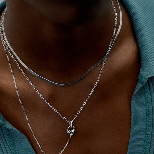 Mio Chain in Silver. Its sinuous, snake-like chain design drapes gracefully around the neck, creating a captivating visual statement. The adjustable length ensures a comfortable fit, allowing you to personalize your style.