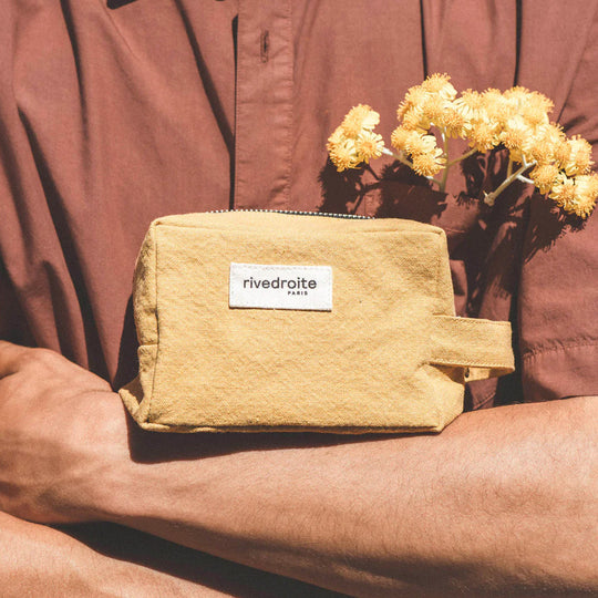 Mustard Tournelles bag from Parasian brand Rive Droite is a compact everyday toiletry make up bag made from re-cycled cotton. Lifestyle image