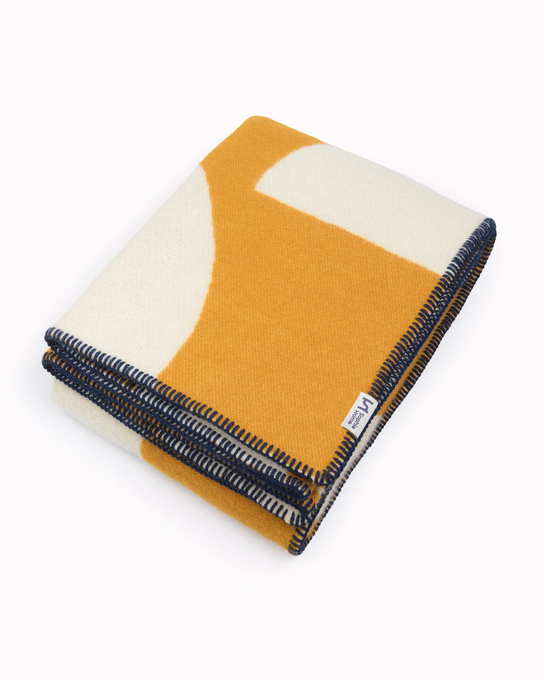 A modern throw in with graphic pattern in mustard and white that sits somewhere between functional and decorative