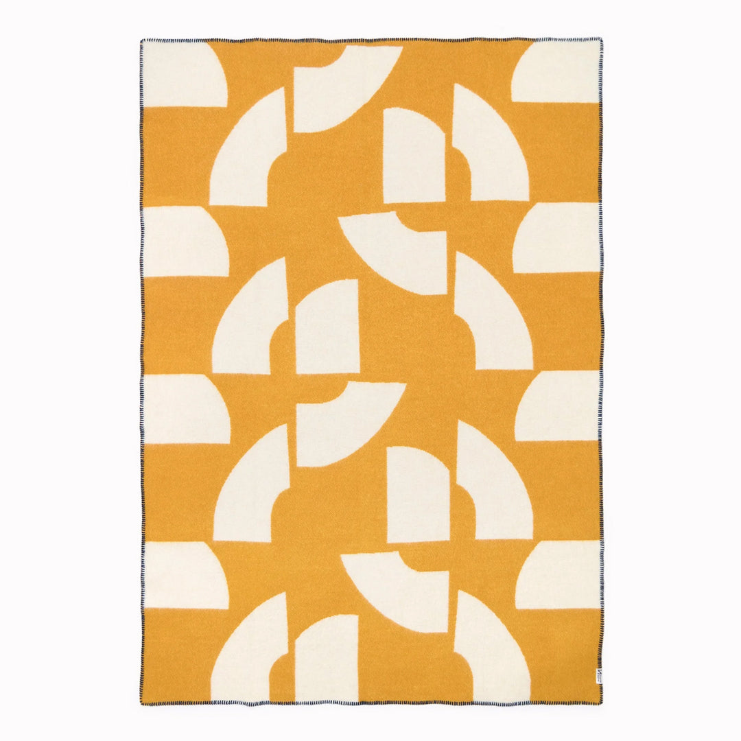A modern throw in with graphic pattern in mustard and white that sits somewhere between functional and decorative