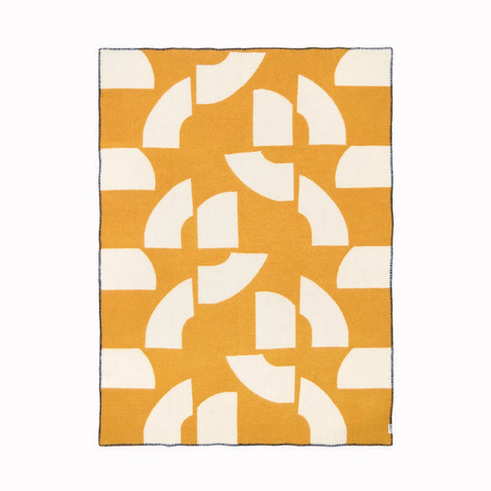 A modern throw in with graphic pattern in mustard and white that sits somewhere between functional and decorative