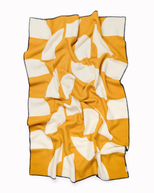 A modern throw in with graphic pattern in mustard and white that sits somewhere between functional and decorative