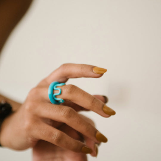 As worn by model, Nell is a turquoise blue handblown glass ring, handmade by Eyland Jewellery, who produce contemporary and colourful pieces of costume jewellery.