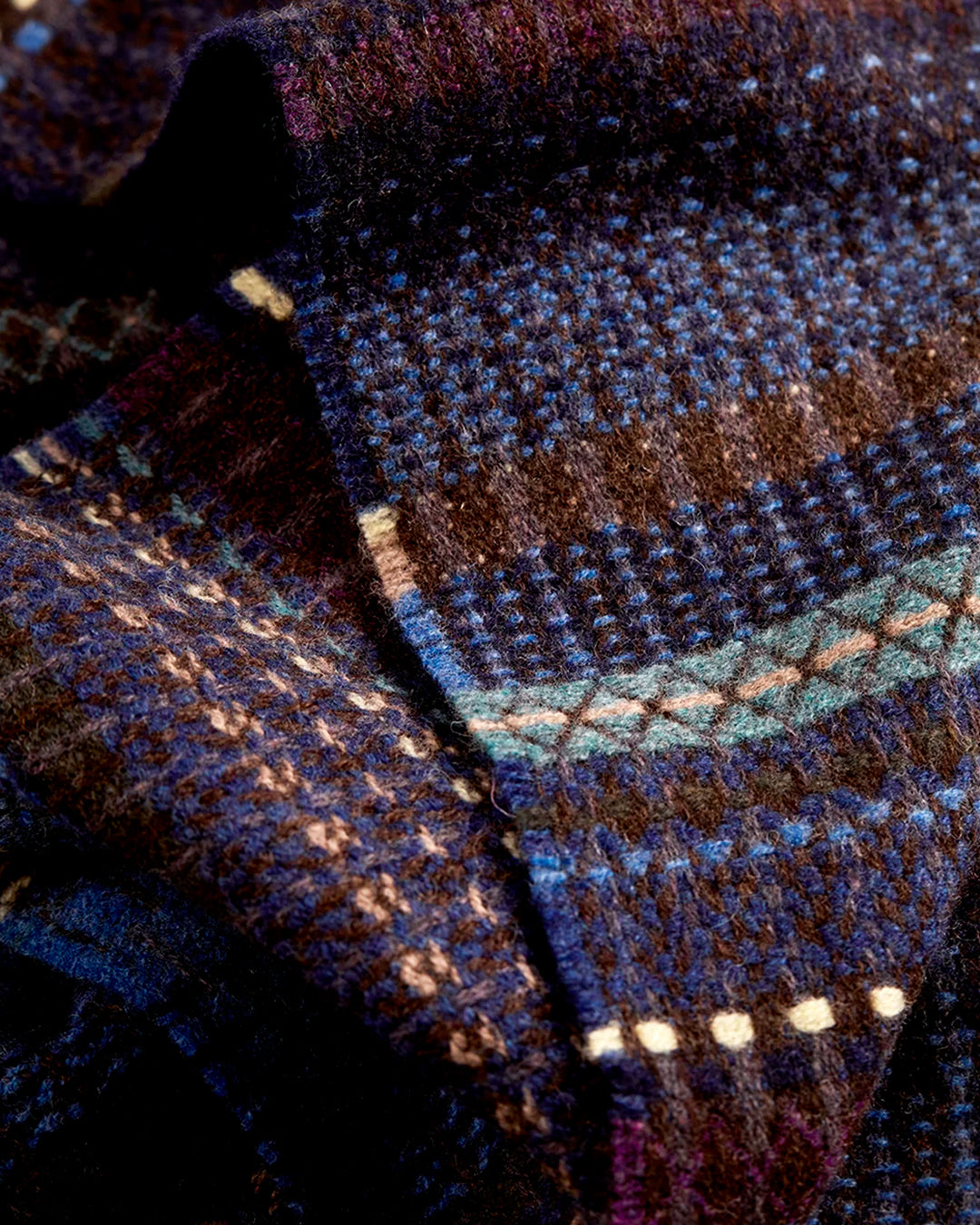 The Noah scarf features a subtle textured weave of background colour offset by intricate detailing at the borders, where delicate floral motifs and patterns mingle with bold cross-hatches, contrasting pinstripes, and graphic bands.&nbsp;