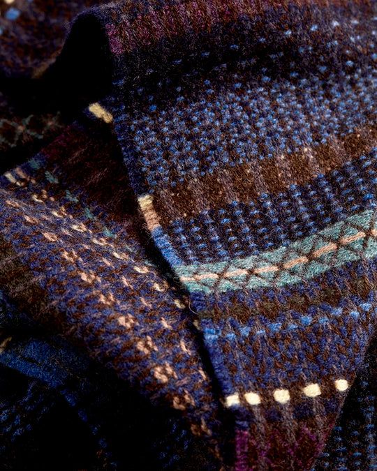 The Noah scarf features a subtle textured weave of background colour offset by intricate detailing at the borders, where delicate floral motifs and patterns mingle with bold cross-hatches, contrasting pinstripes, and graphic bands.&nbsp;