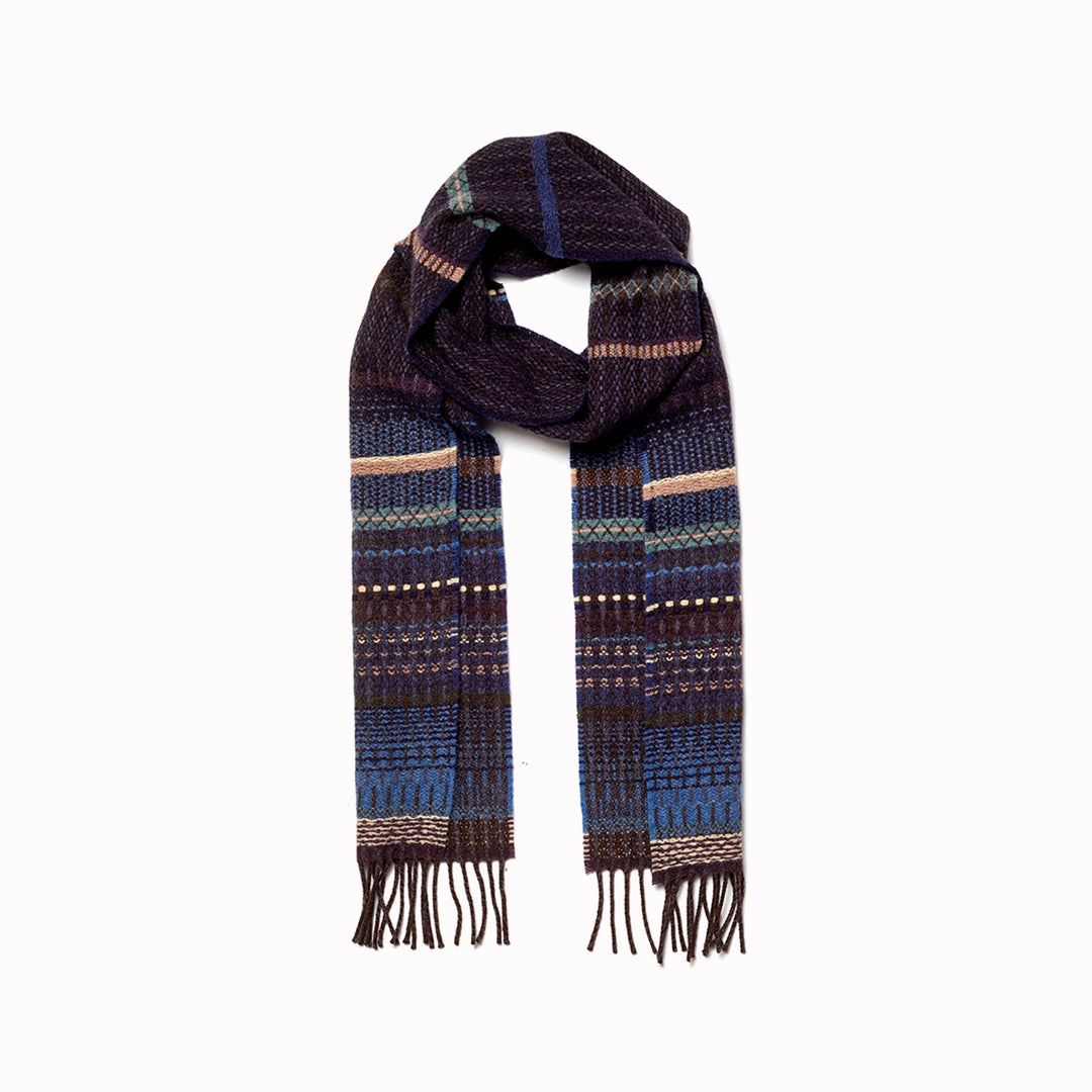 The Noah scarf features a subtle textured weave of background colour offset by intricate detailing at the borders, where delicate floral motifs and patterns mingle with bold cross-hatches, contrasting pinstripes, and graphic bands.&nbsp;