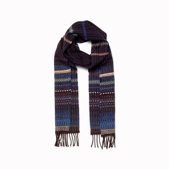 The Noah scarf features a subtle textured weave of background colour offset by intricate detailing at the borders, where delicate floral motifs and patterns mingle with bold cross-hatches, contrasting pinstripes, and graphic bands.&nbsp;