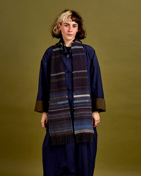 The Noah scarf features a subtle textured weave of background colour offset by intricate detailing at the borders, where delicate floral motifs and patterns mingle with bold cross-hatches, contrasting pinstripes, and graphic bands.&nbsp;