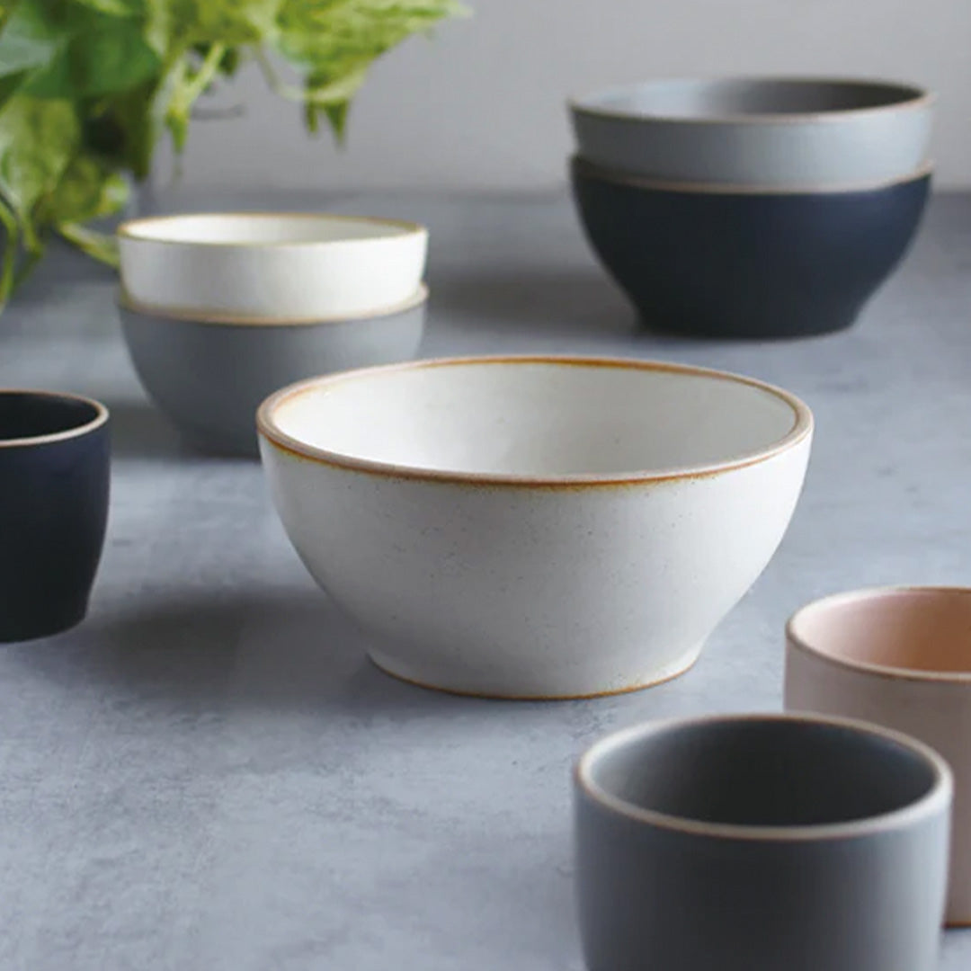 The Black Nori Porcelain Tumbler is a Japanese manufactured small tea, coffee, or juice cup from Kinto. The porcelain has a tactile sloping side and smooth finish which feels pleasing in your hands. The glaze is a tasteful matt black stone with raw porcelain edges in the Japanese style. Lifestyle shot, Nori cups and bowls.