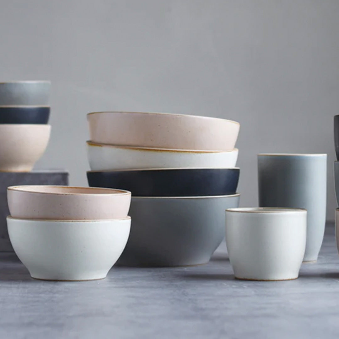The Black Nori Porcelain Tumbler is a Japanese manufactured small tea, coffee, or juice cup from Kinto. The porcelain has a tactile sloping side and smooth finish which feels pleasing in your hands. The glaze is a tasteful matt black stone with raw porcelain edges in the Japanese style. Lifestyle shot, Nori cups and bowls.