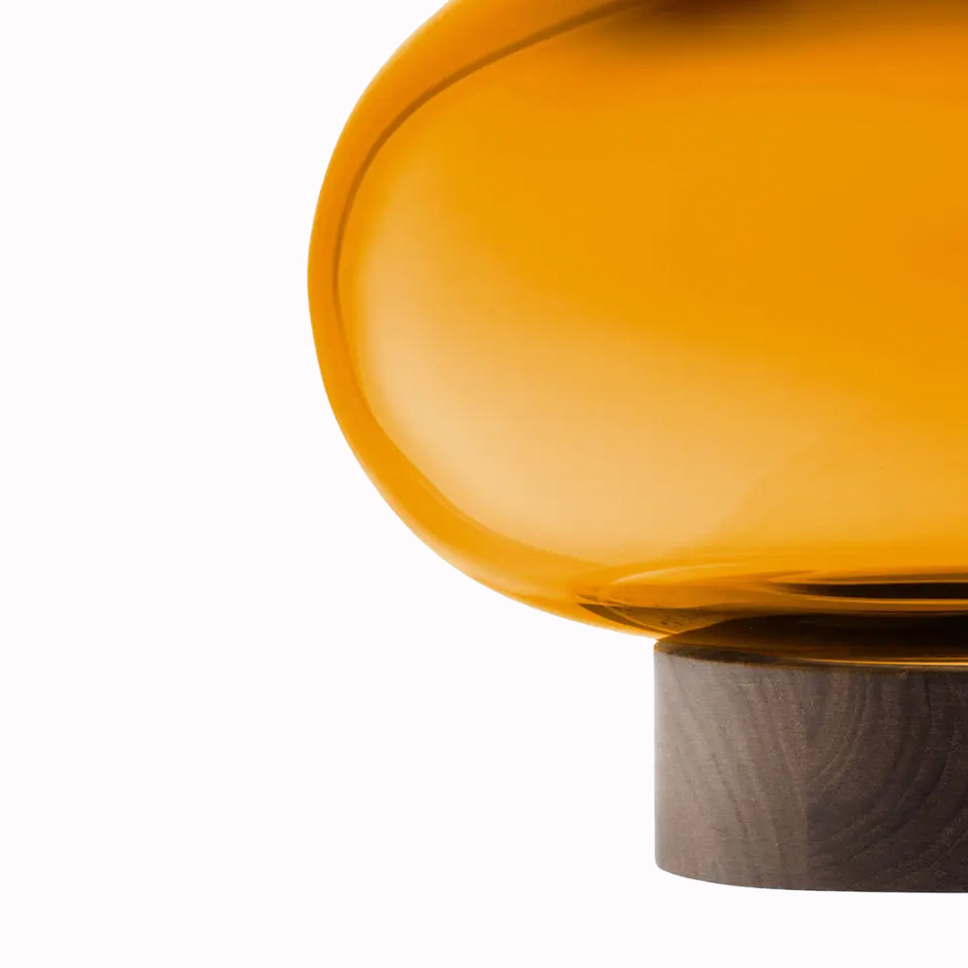 A flattened spherical mouth blown Amber glass vessel sits on a Walnut wood base. This is a beautiful and versatile piece, suitable for use as a vase, or as a candle lantern