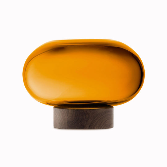 A flattened spherical mouth blown Amber glass vessel sits on a Walnut wood base. This is a beautiful and versatile piece, suitable for use as a vase, or as a candle lantern
