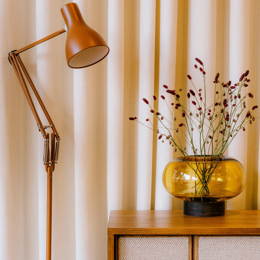 A flattened spherical mouth blown Amber glass vessel sits on a Walnut wood base. This is a beautiful and versatile piece, suitable for use as a vase, or as a candle lantern