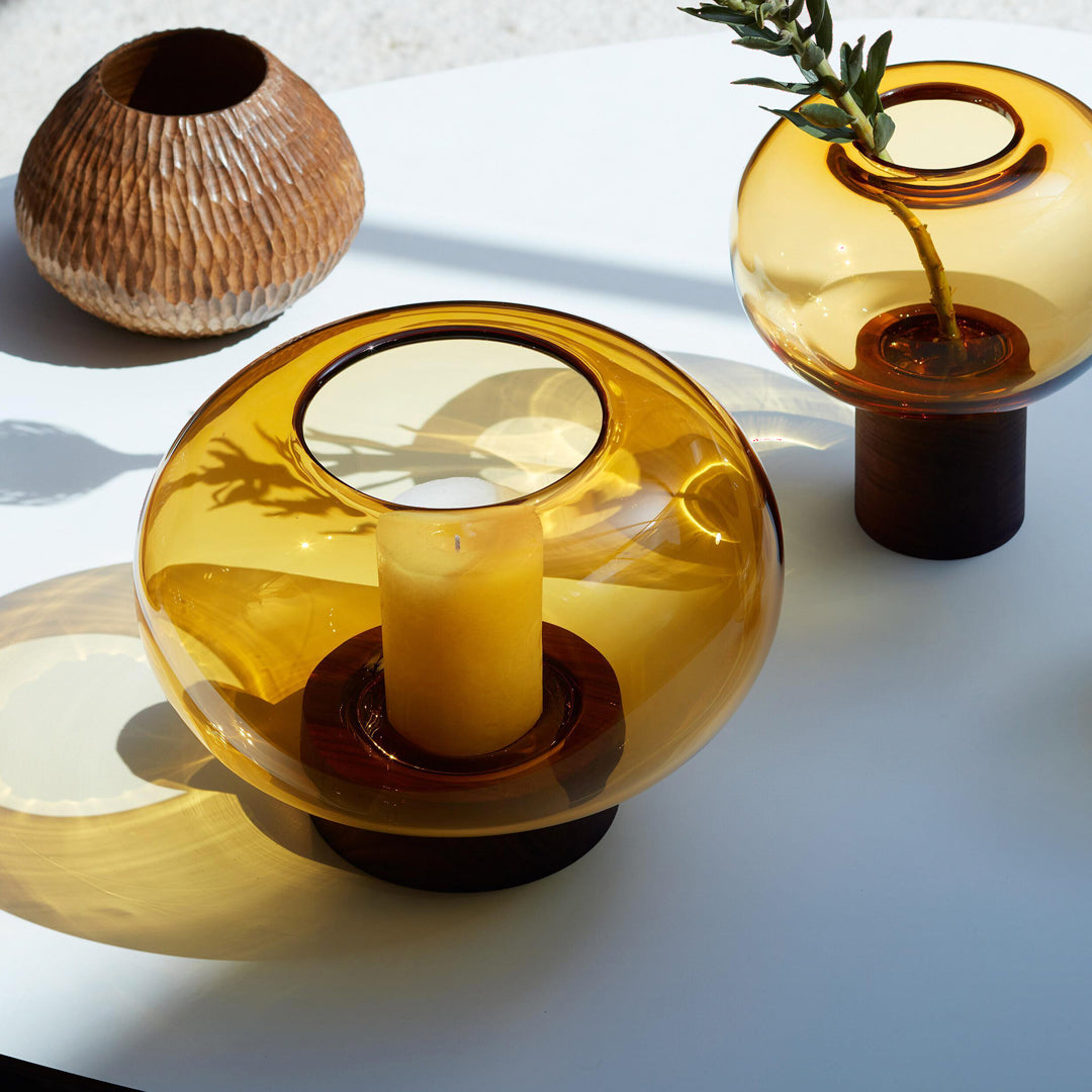 A flattened spherical mouth blown Amber glass vessel sits on a Walnut wood base. This is a beautiful and versatile piece, suitable for use as a vase, or as a candle lantern