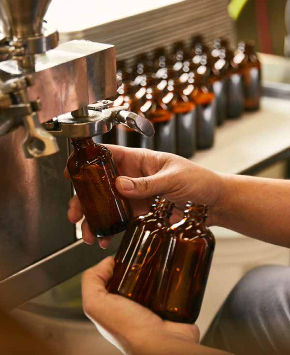 PF Candle Co behind the scenes showing the fragrance bottling process being done by hand
