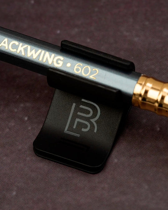 The Blackwing Pencil Holder is a simple metal clip designed to attach securely to the cover of your favourite notebook, giving your pencil a dedicated place to live.
