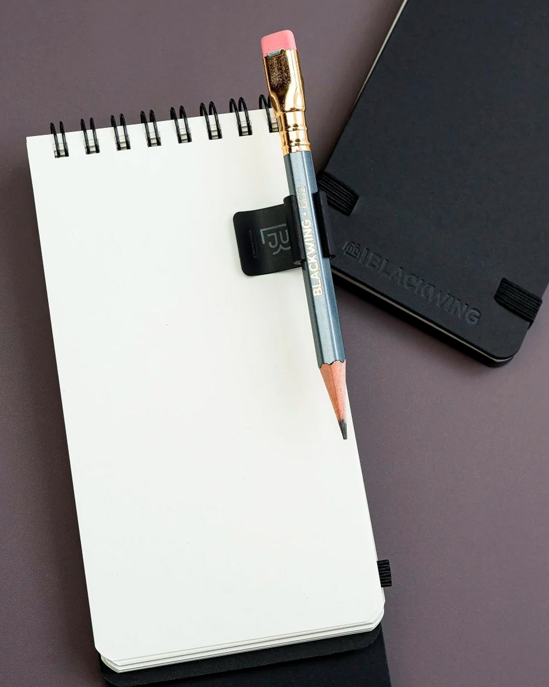The Blackwing Pencil Holder is a simple metal clip designed to attach securely to the cover of your favourite notebook, giving your pencil a dedicated place to live.