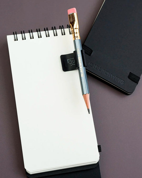 The Blackwing Pencil Holder is a simple metal clip designed to attach securely to the cover of your favourite notebook, giving your pencil a dedicated place to live.