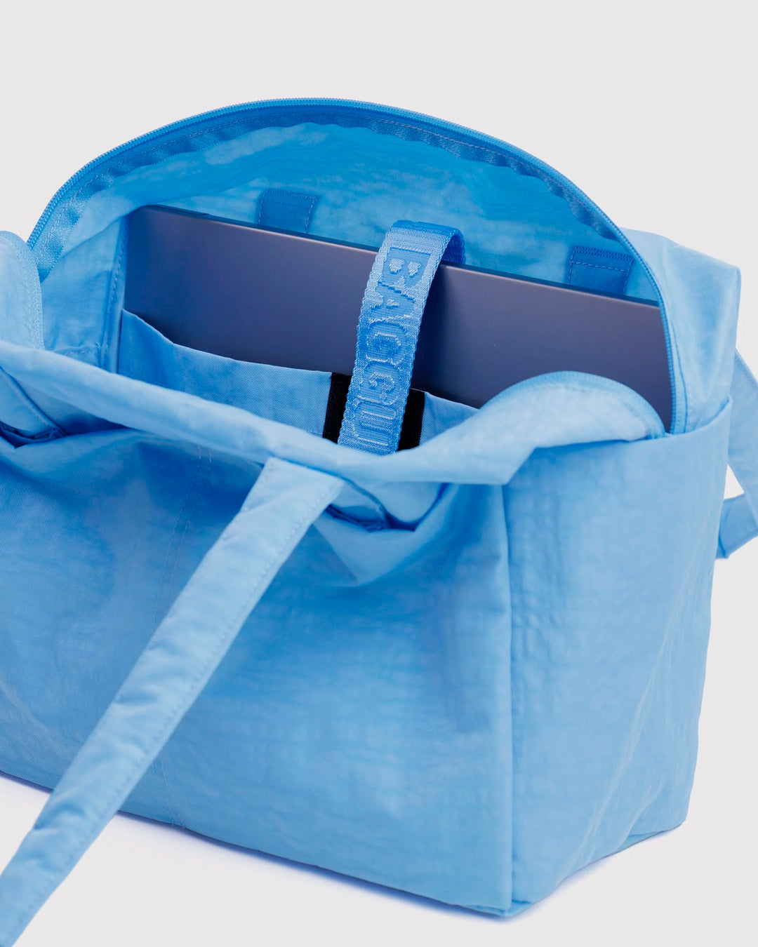 Made from recycled heavyweight nylon, it holds its shape without feeling rigid. The layout is considered: a zipped laptop sleeve sits to one side