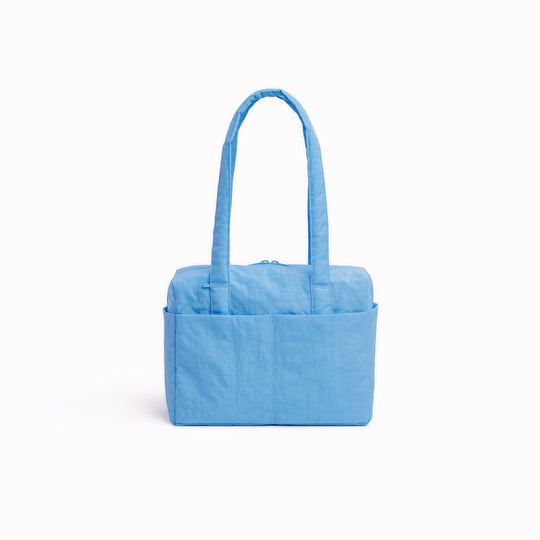 Made from recycled heavyweight nylon, it holds its shape without feeling rigid. The layout is considered: a zipped laptop sleeve sits to one side