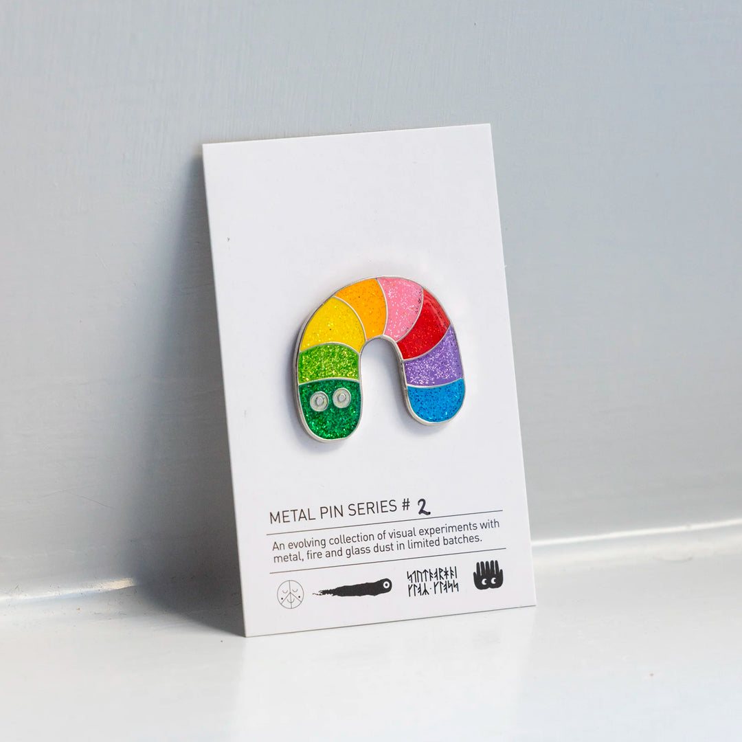 A limited edition collectible Rainbow Worm design pin badge by Studio Arhoj, from their Series 2 edition. This design comes with added sparkle, using a glitter enamel