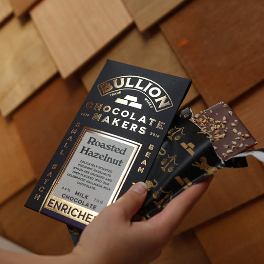 Delicately roasted piedmont hazelnuts are crushed and then flecked into this celebrated Hallmark Milk Chocolate chocolate from Bullion. Shown in hand.