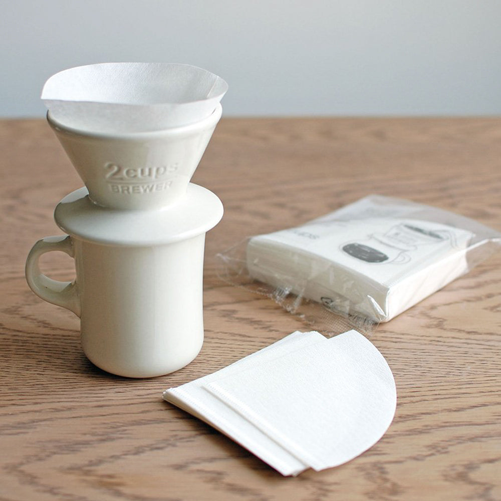 White Porcelain slow coffee cup brew attachment with filter papers from Kinto, placed over a mug with a filter paper inside.