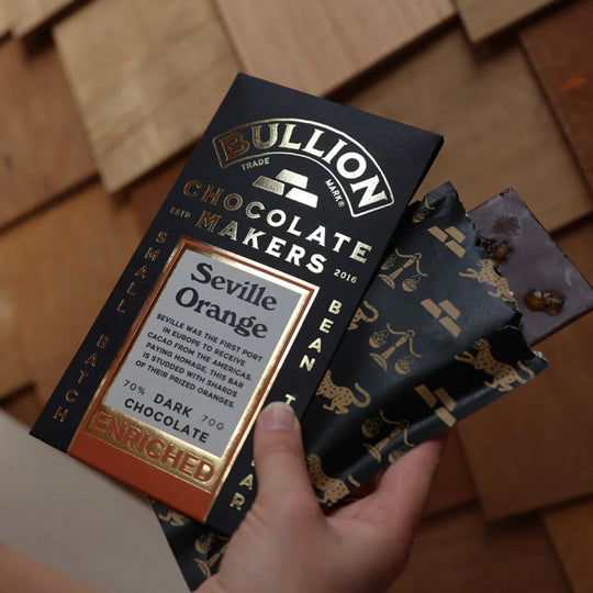 Seville was the first port in Europe to receive cacao from the Americas. Paying homage, this bar from Bullion Chocolate is studded with shards of their prized oranges.. shwon in hand.