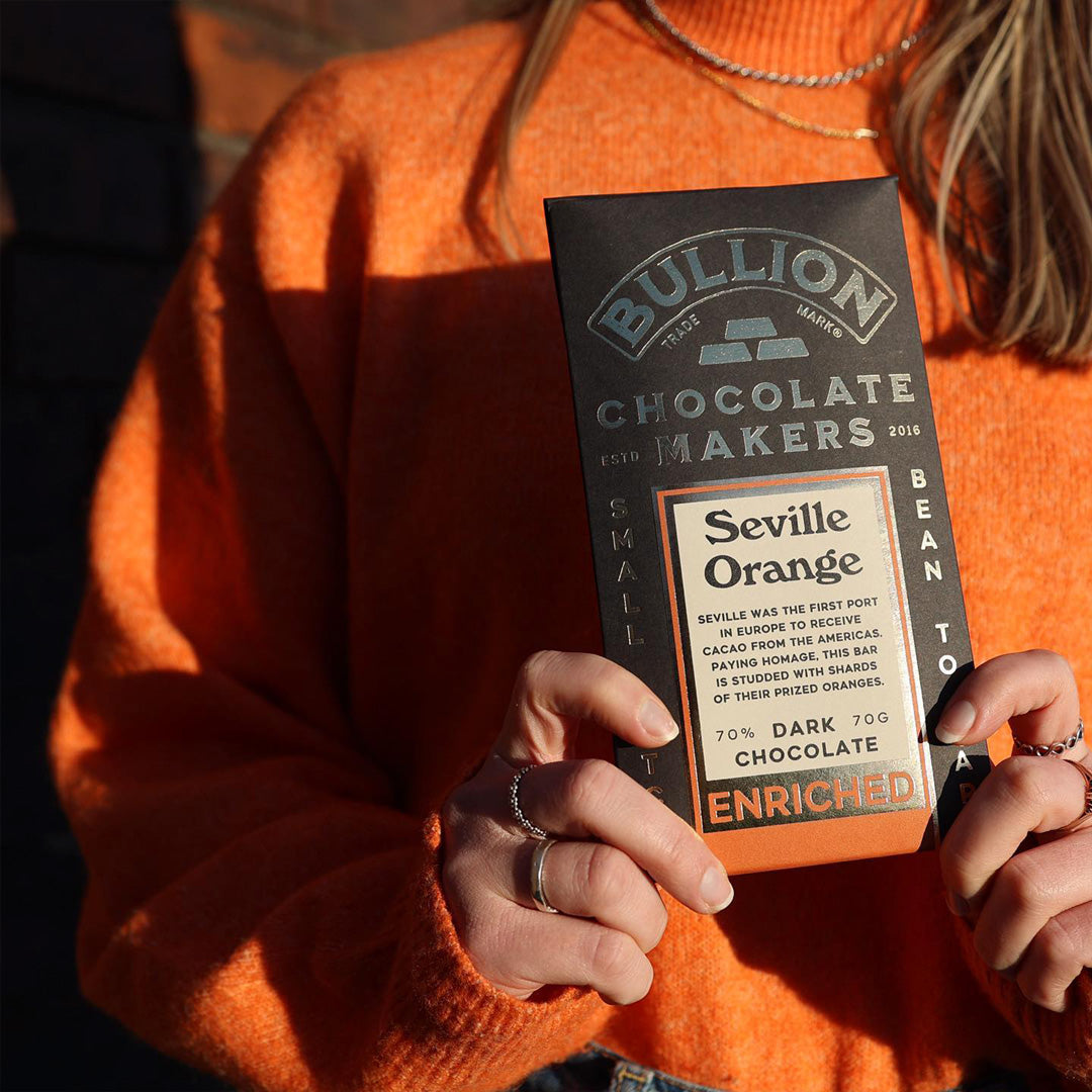 Seville was the first port in Europe to receive cacao from the Americas. Paying homage, this bar from Bullion Chocolate is studded with shards of their prized oranges. - held by model