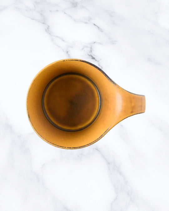 The Stamug is a porcelain mug with 150ml capacity for tea or shorter coffee drinks. Finished in a matt mustard glaze mixed with earthy brown tones.