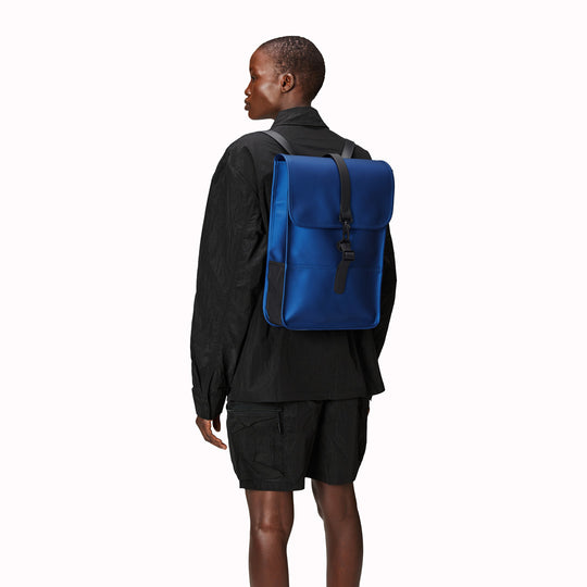 Storm Blue Mini Backpack from the Rains SS24 colour palette. Made from Rains' signature water-resistant fabric with a matte finish, this minimalistic, modern rucksack is called 'Mini' but is the perfect size for daily use. As Worn.