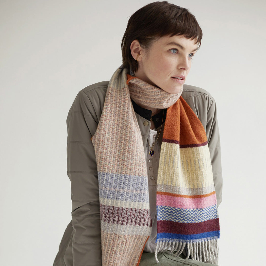 As Worn - The Strathay Amber Lambswool scarf by Wallace and Sewell is a 100% Merino Lambswool scarf in a colourful pattern of Ambers, Bubblegum Pink and Buttercup Yellow.